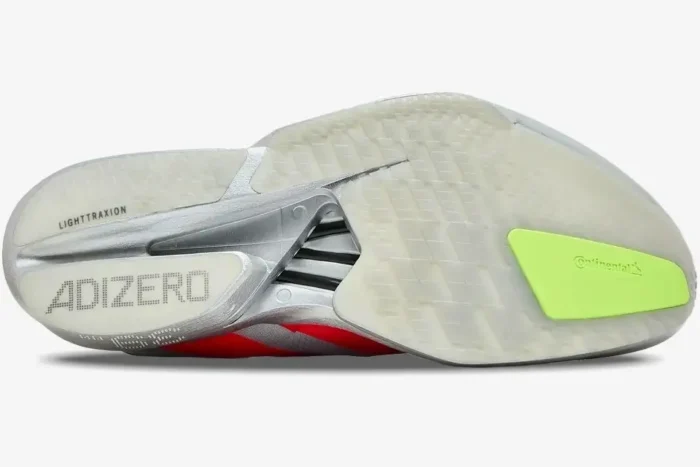 Bottom view of the Adidas Adizero Adios Pro 4 in silver and red, showing the textured outsole and Continental rubber. - SKU JR6357