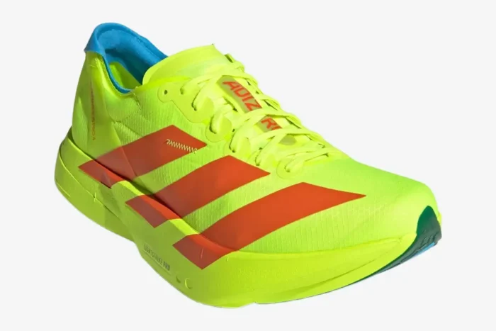 Three-quarter view of the Adidas Adizero Adios Pro 4 running shoe in neon yellow with orange stripes. - SKU JQ1571