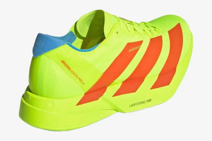 Rear-side view of a yellow and orange Adidas Adizero Adios Pro 4 running shoe with blue heel detail. - SKU JQ1571