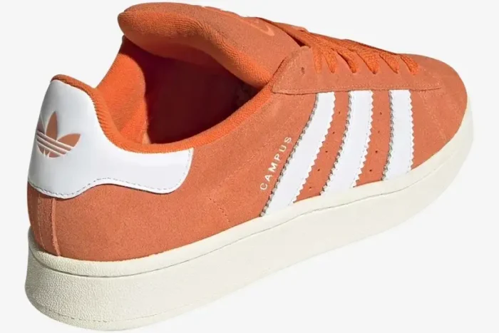 Rear view of Adidas Campus 00s Amber Tint Orange shoes featuring white serrated stripes and a chunky cream sole. - SKU ID1436