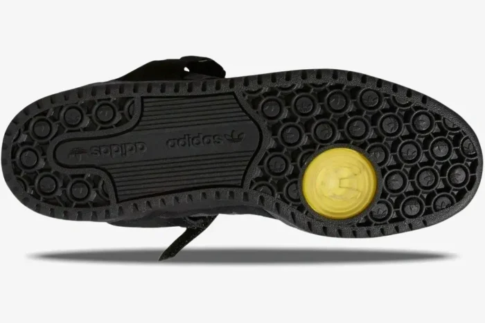 Bottom view of the black Adidas Forum Buckle Low x Bad Bunny sneaker sole with a yellow pivot point. - SKU GW5021