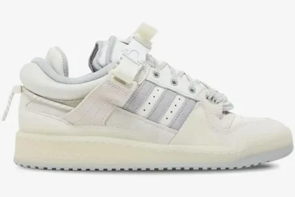 A side profile view of the Adidas Forum Buckle Low x Bad Bunny White Cream sneaker with a buckle strap. - SKU HQ2153
