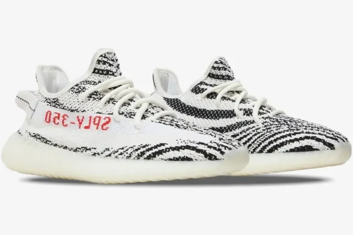 Side profile view of Adidas Yeezy Boost 350 V2 Zebra sneakers with white and black knit and red text. - SKU CP9654