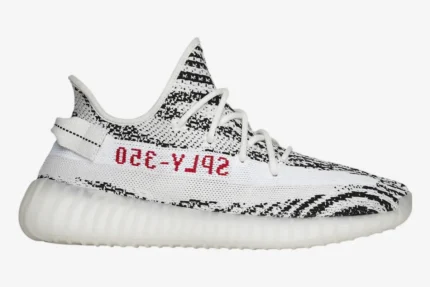 Side profile of Adidas Yeezy Boost 350 V2 Zebra sneakers with white and black knit upper and red SPLY-350 text. - SKU CP9654