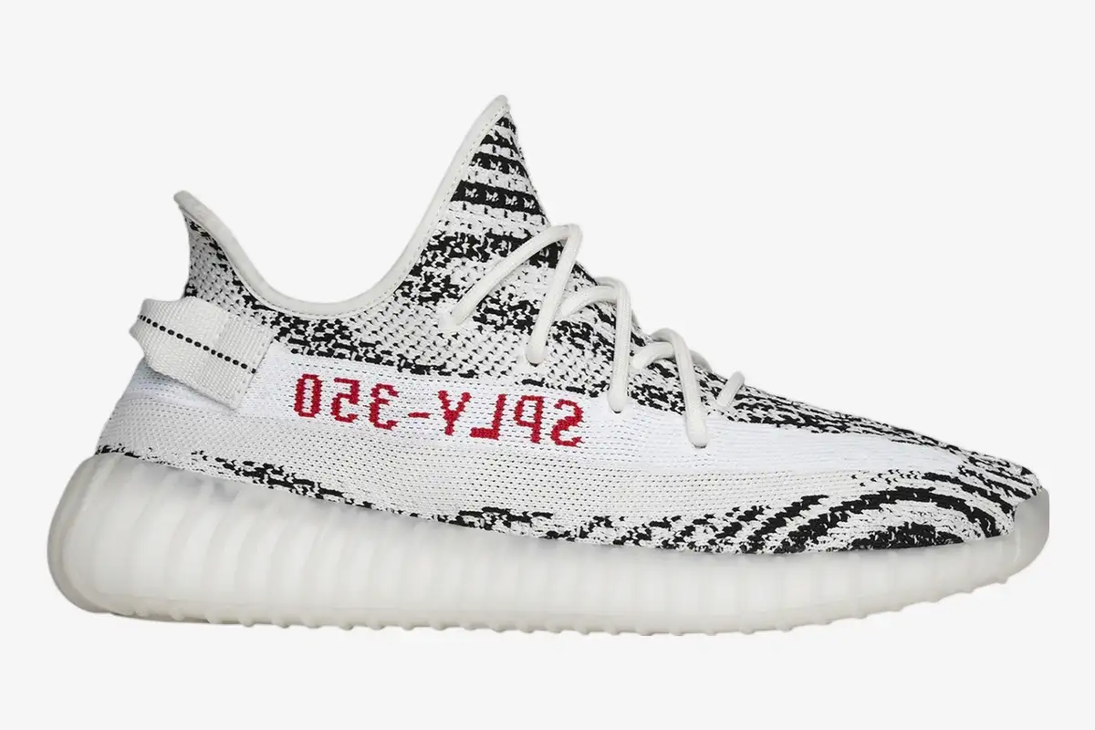adidas-yeezy-boost-350-v2-zebra-side-view-cp9654-117-179 Side profile of Adidas Yeezy Boost 350 V2 Zebra sneakers with white and black knit upper and red SPLY-350 text. - SKU CP9654