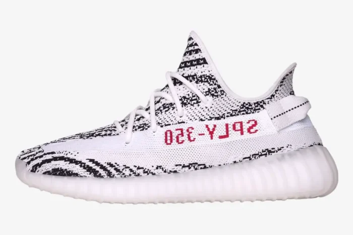 Side profile of Adidas Yeezy Boost 350 V2 Zebra sneakers featuring white and black Primeknit and red SPLY-350 text. - SKU CP9654