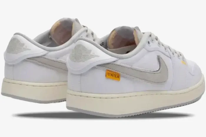 Rear-side view of Air Jordan 1 Low x Union LA sneakers in white and neutral grey with yellow UN/LA tag. - SKU DO8912-101