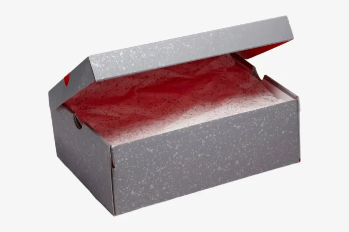 Open grey speckled Air Jordan 4 Retro Infrared shoebox with red interior and tissue paper, angled view. - SKU DH6927-061