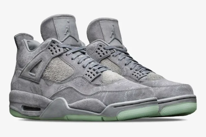 Air Jordan 4 Retro x Kaws Cool Grey sneakers in a three-quarter side view with glow-in-the-dark soles. - SKU 930155-003