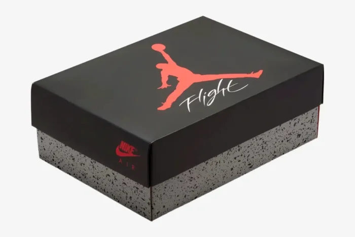 Three-quarter view of the Air Jordan 4 Retro White Cement shoebox with black lid and grey cement print. - SKU 840606-192