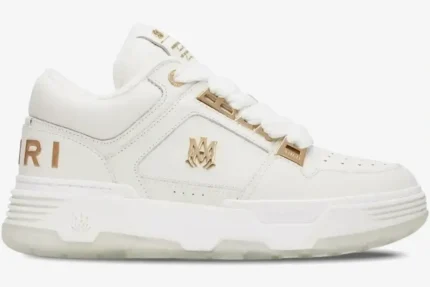 Amiri MA-1 Metallic White Gold sneaker in a side profile view featuring gold logo accents and a chunky sole. - SKU 252886M237010