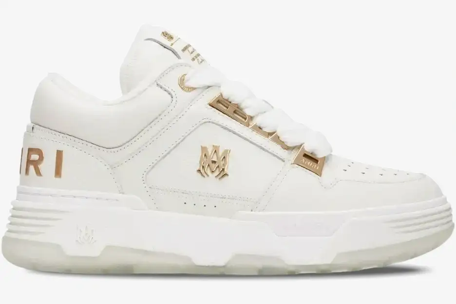amiri-ma1-metallic-white-gold-side-view-252886m237010-993-550 Amiri MA-1 Metallic White Gold sneaker in a side profile view featuring gold logo accents and a chunky sole. - SKU 252886M237010