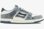 Side profile of Amiri Skel Top Low sneakers featuring blue denim skeleton patches on white leather. - SKU pf23mfs007-533