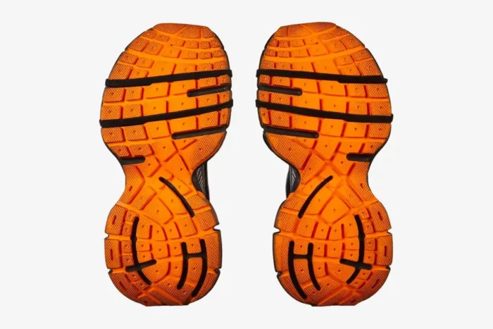 Bottom view of Balenciaga 3XL sneakers showing bright orange textured rubber outsoles with black details. - SKU 734734W3XL31178