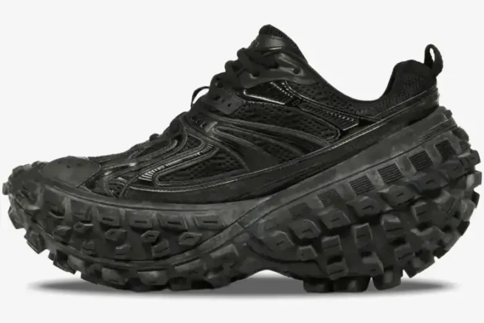 Side profile of a Balenciaga Defender chunky sneaker in black with a massive tire-tread sole. - SKU 685613W2RA61000