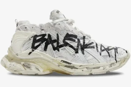Side profile of a Balenciaga Runner Graffiti sneaker in white and black with a distressed look. - SKU 677403W3RBQ9010