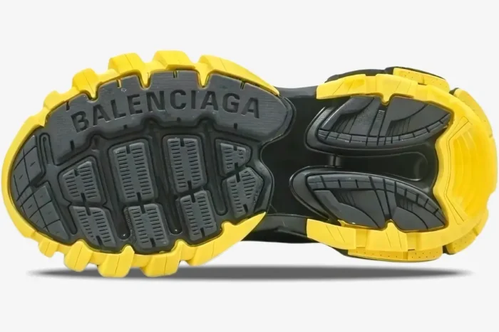 Bottom view of a Balenciaga Track sneaker in black and yellow, showing the chunky lugged outsole. - SKU 542023W3AC11070