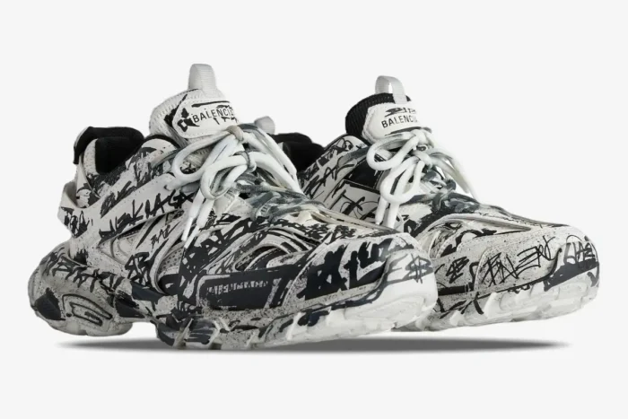 Balenciaga Track sneakers in white and black with graffiti print, shown from a three-quarter front angle. - SKU 542023W3RRA9010