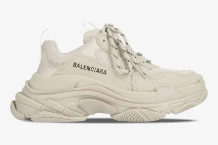 Side profile view of a cream-colored Balenciaga Triple S sneaker with a signature chunky platform sole. - SKU 524039W2FW19700