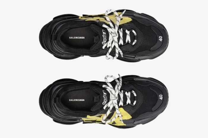 Top-down view of black Balenciaga Triple S Tapa Type sneakers featuring yellow tape accents and white laces. - SKU 536737WTRST1070