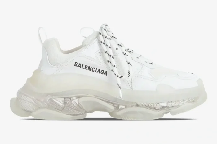 Side profile of a white Balenciaga Triple S sneaker featuring a chunky clear sole and black logo. - SKU 544351W2FB19000