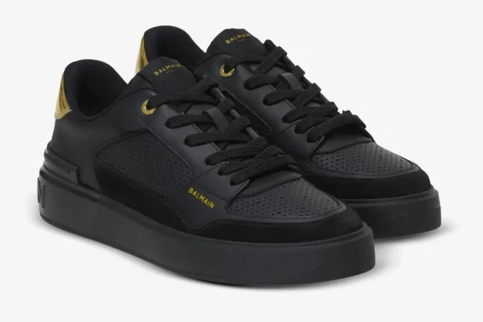 Balmain B-Court Flip low-top sneakers in black and gold, shown from a three-quarter front perspective. - SKU DN0VI727LBSO