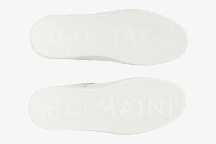 Underside view of white Balmain B-Court Trainer soles with embossed logo and herringbone pattern. - SKU GM1VI288LVTR