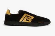 Side view of Balmain Swan black suede sneakers with a large metallic gold logo and gold heel tab. - SKU AM1VI261LSGG