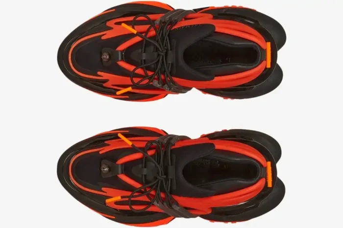 Top-down view of Balmain Unicorn Low-Top sneakers in vibrant orange and black with chunky soles and black laces. - SKU YM1VJ309KNCA