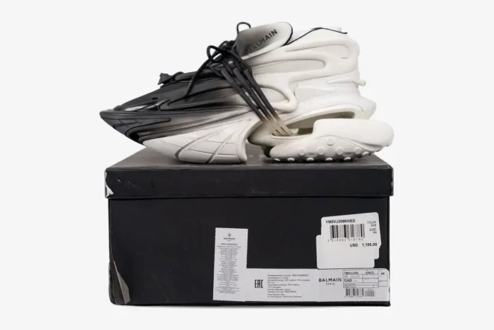 Balmain Unicorn Low Top white and black gradient sneakers on a black box, side profile view. - SKU YM0VJ309KNED-GAB