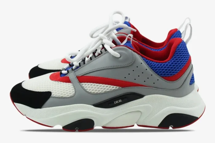 Side view of Dior B22 luxury sneakers in grey, red, and blue with a chunky white midsole. - SKU 3SN231YKB_H865