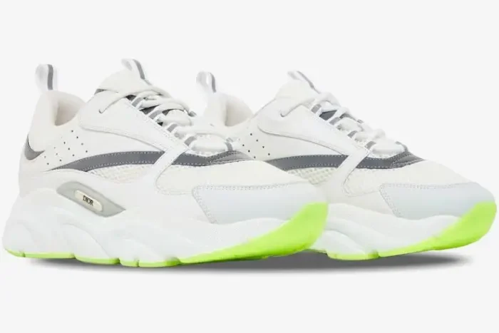 Side profile of Dior B22 sneakers in white and silver featuring a vibrant fluorescent green outsole. - SKU 3SN231YKA_H000