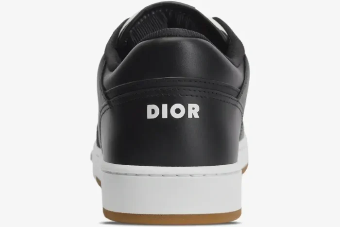 Rear view of a black Dior B27 low top sneaker featuring a white logo on the leather heel and a gum sole. - SKU 3SN272ZIR_H965