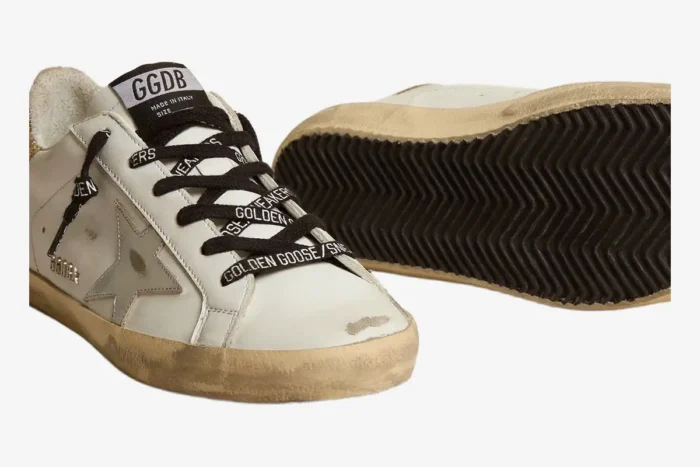 White Golden Goose Super-Star sneakers with black logo laces and distressed soles, angled front view. - SKU GWF00102
