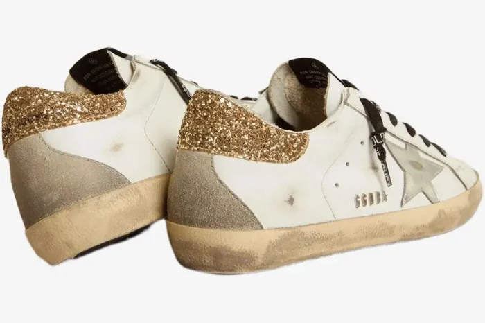 Rear view of Golden Goose Super-Star sneakers in white with gold glitter heel tabs and distressed soles. - SKU GWF00102