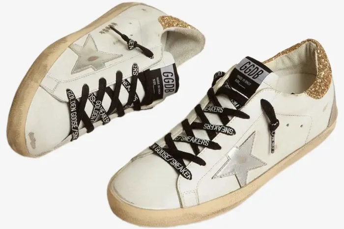 Angled top view of white Golden Goose Super-Star sneakers featuring silver stars and gold glitter heel tabs. - SKU GWF00102
