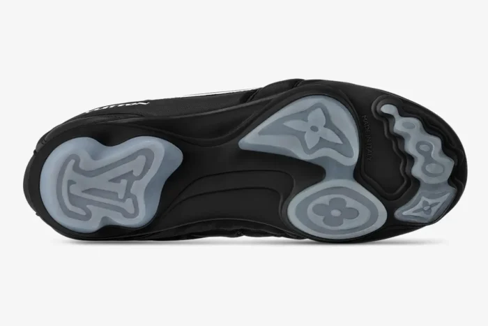 Bottom view of black Louis Vuitton Footprint Soccer Shoes showing grey monogram patterned outsoles.