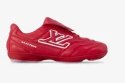 Side profile of a red leather Louis Vuitton Footprint soccer shoe with white LV logo.