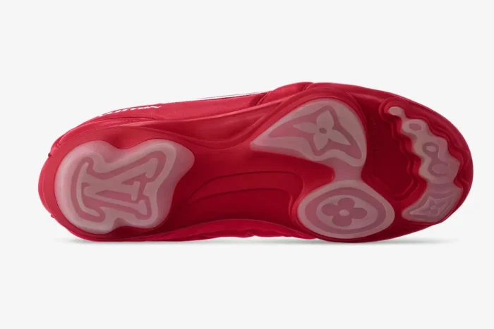 Bottom sole view of red Louis Vuitton Footprint soccer shoes with translucent monogram patterns.
