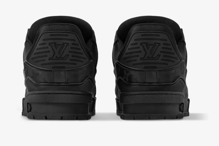 Rear view of Louis Vuitton LV Trainer in black monogram leather showing the embossed heel logo. - SKU 1AHDBK