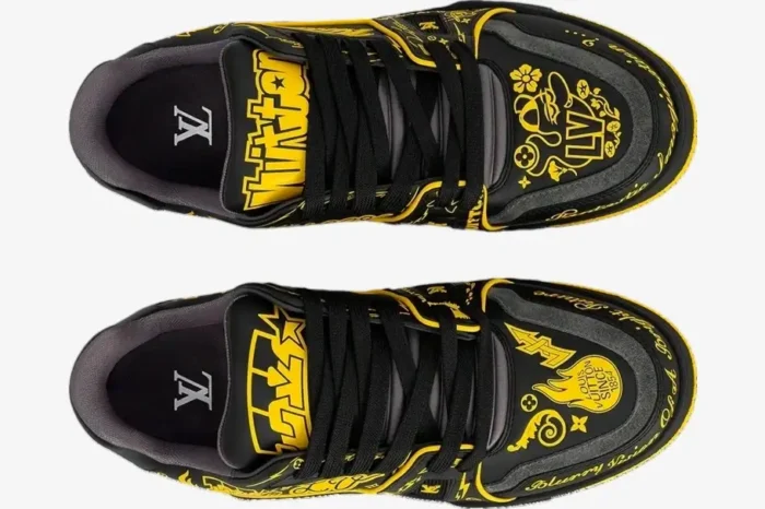 Top-down view of black and yellow Louis Vuitton LV Trainer sneakers with bold graffiti graphics. - SKU 1A9JTV