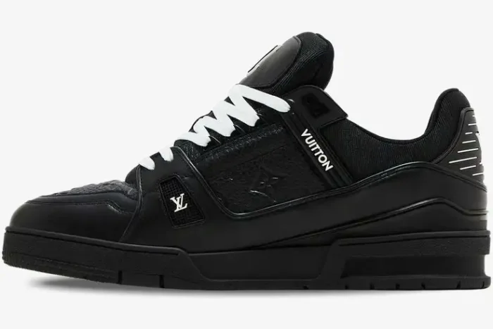 Side profile of a black Louis Vuitton LV Trainer sneaker with white laces and monogram leather details. - SKU 1A9JG9