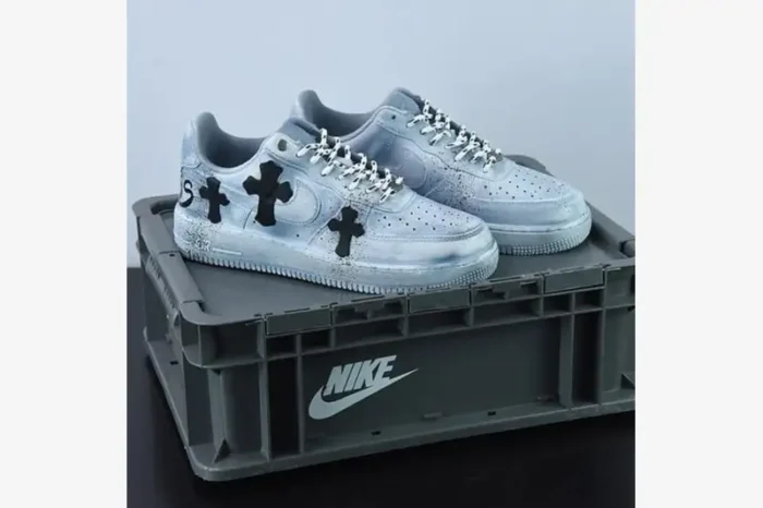 Custom light blue Nike Air Force 1 sneakers with black crosses on a grey Nike crate, three-quarter view.