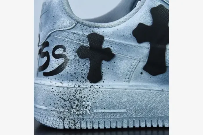 Close-up of a silver custom Air Force 1 featuring black Chrome Hearts cross patches and paint splatter details.