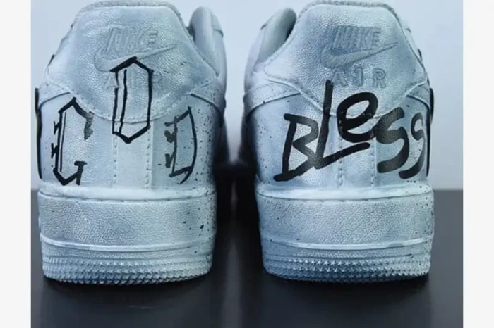 Rear view of custom metallic silver Nike Air Force 1 sneakers with 'GOD BLESS' graffiti text in black.