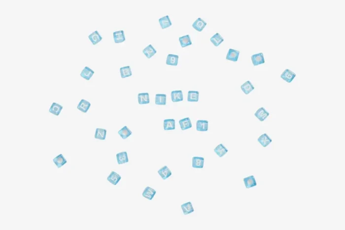 Top-down view of light blue translucent letter beads spelling NIKE and AF1 for NOCTA sneakers. - SKU CZ8065-100