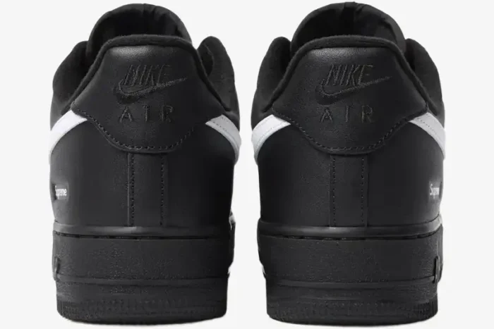 Rear view of Nike Air Force 1 Low x Supreme sneakers in black with white swoosh and heel branding. - SKU SP1AF11