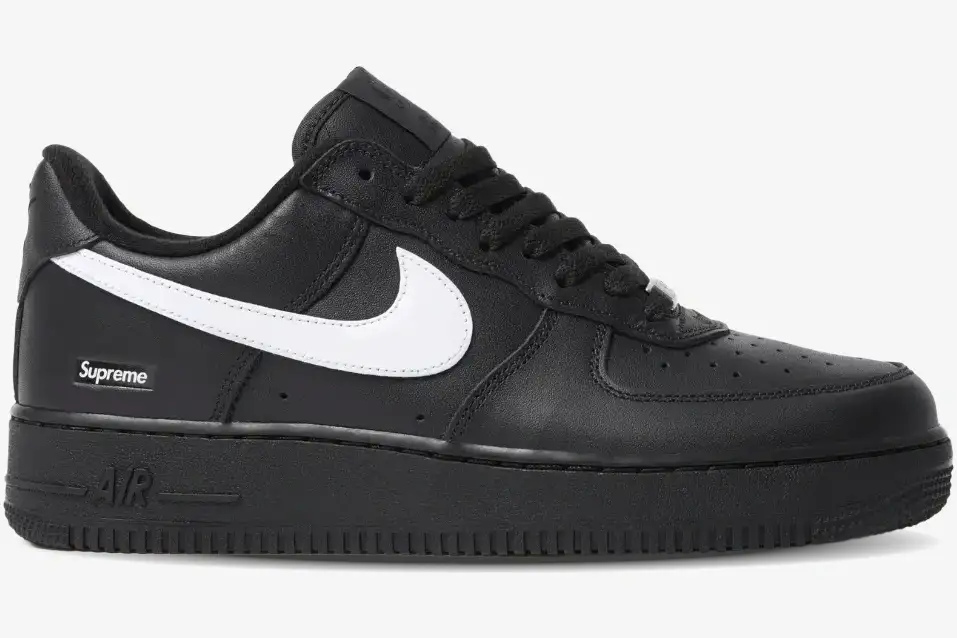 nike-air-force-1-low-supreme-black-white-side-sp1af11 Side profile of Nike Air Force 1 Low x Supreme in black with a white swoosh and heel logo. - SKU SP1AF11
