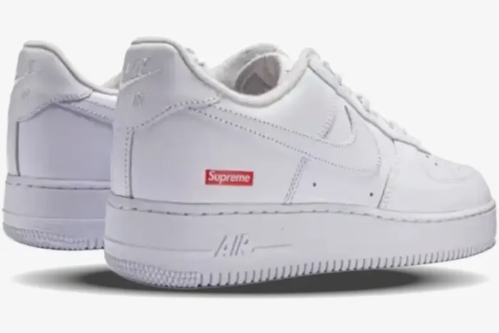 Rear three-quarter view of Nike Air Force 1 Low x Supreme White sneakers with red box logo on the heel. - SKU CU9225-100