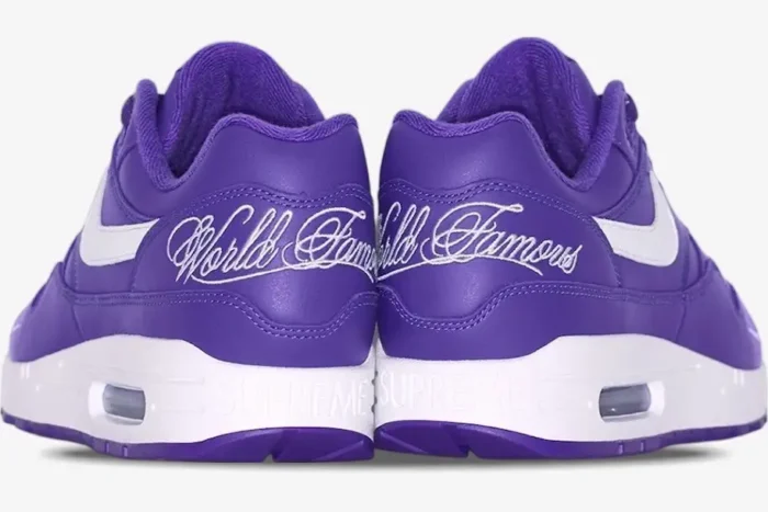 Rear view of purple and white Nike Air Max 1 x Supreme sneakers with World Famous heel embroidery. - SKU HF8813-500